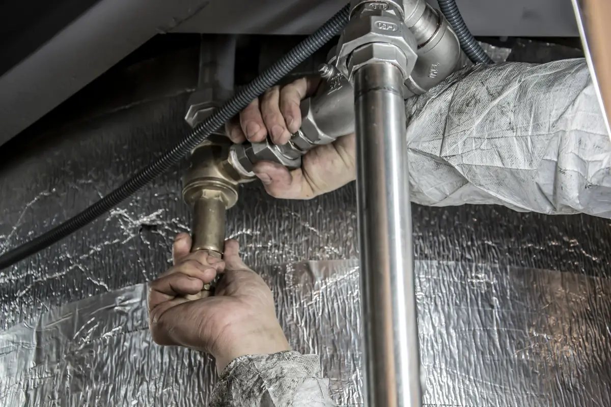 A plumber fixing pipes beneath a sink